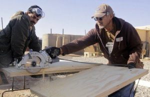 two men cutting wood using a band saw