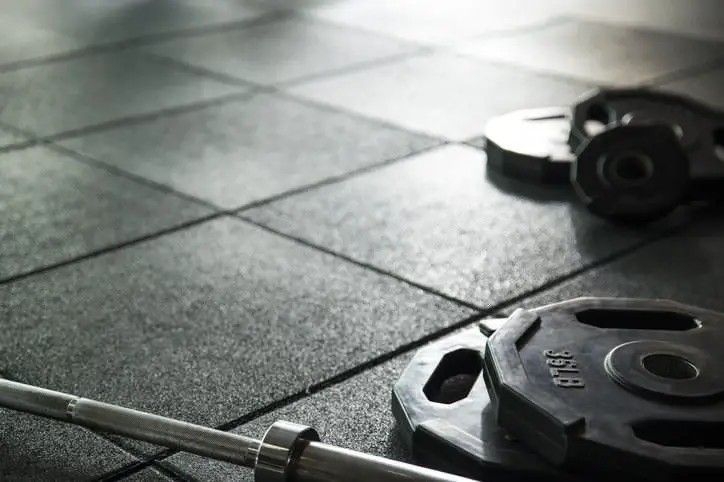 empty barbell and weights plates sat on rubber gym floor