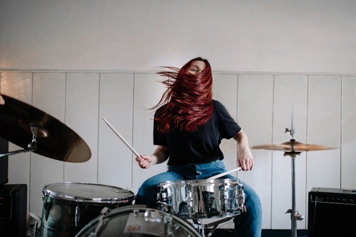 woman vigorously playing acoustic drums