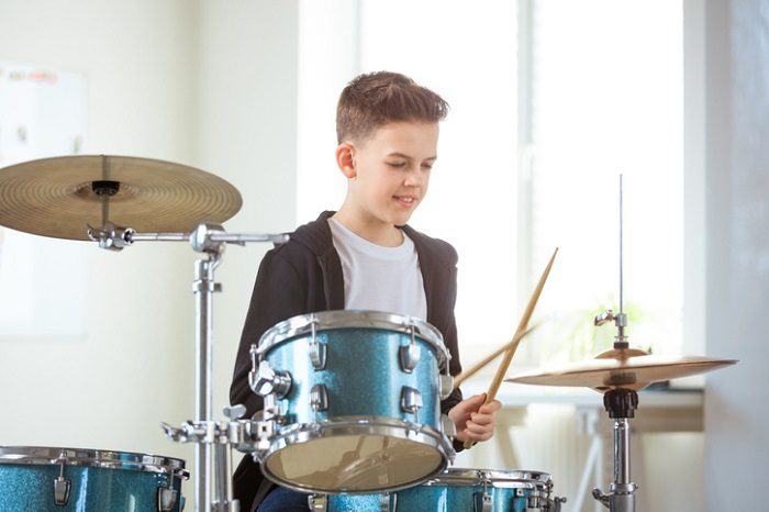 young teenager practicing drums at home